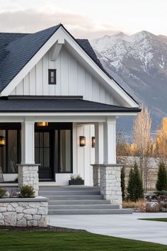 a white house with black roof and steps leading up to the front door that is surrounded by grass