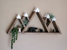 three wooden shelves with plants and animals on them in front of a wall mounted planter