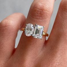 a woman's hand holding an engagement ring with two diamonds on it, and the middle