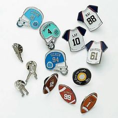 many different sports pins and badges on a white surface with one being a football, the other is a jersey