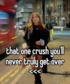 a woman standing on the side of a road next to a red bus