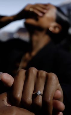 a close up of a person's hand with a diamond ring on their finger