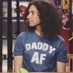 a man with long curly hair wearing a daddy af t - shirt