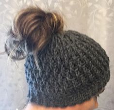 a woman with a messy ponytail wearing a gray knitted hat