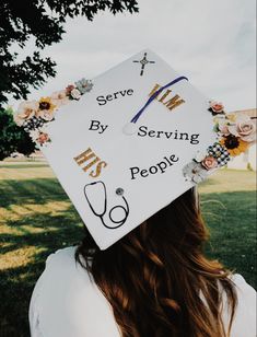 a woman wearing a white graduation cap with flowers on it and the words serve by serving people