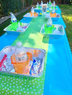 there are many bottles and containers on the table for drinks to be served at an outdoor party