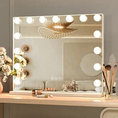 a vanity with lights and flowers on it in front of a mirror that is lit up