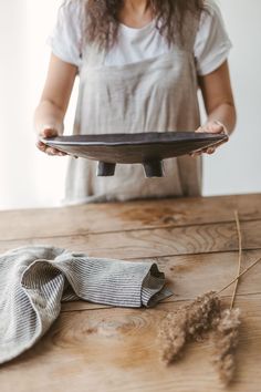 a woman holding a plate on top of a wooden table