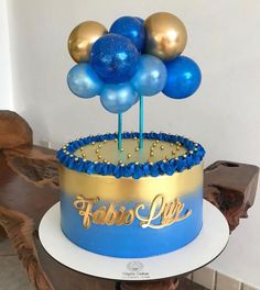 a blue and gold birthday cake with balloons on top