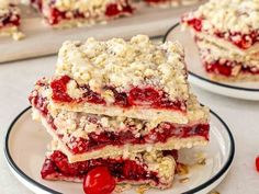 three dessert bars stacked on top of each other with cherries around the edges and crumbled toppings