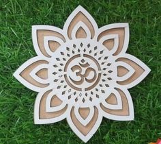 a wooden cutout of a flower with the word om shan on it, sitting in grass