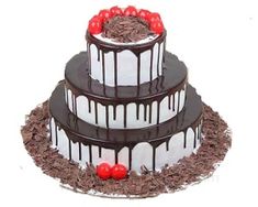 three tier chocolate cake with cherries on top and white icing drizzles