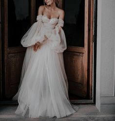 a woman standing in front of a door wearing a white dress