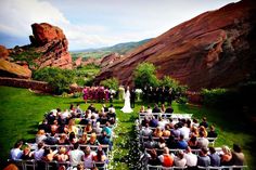 an outdoor wedding ceremony in the mountains with people sitting on chairs looking at each other