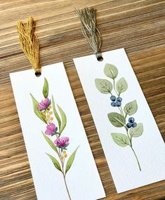 two bookmarks with watercolor flowers and leaves on them, one has a tassel