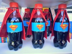 three bottles of soda with superman capes on them sitting on a shelf in a store