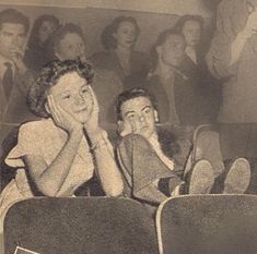 an old black and white photo of two people sitting in a movie theater with their mouths open