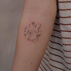 a woman's arm with a small flower tattoo on the left side of her arm