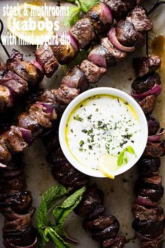 a plate with skewered steaks and a bowl of ranch dressing on it