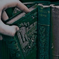 a person holding an open book in front of several books