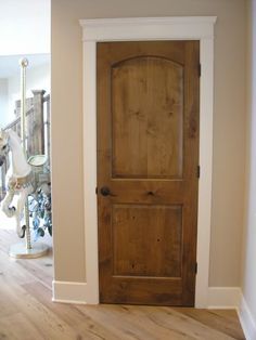 an empty room with a wooden door and horse statue in the background on the floor