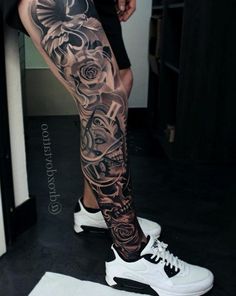 a man's leg with tattoos on it, and his shoes in the background