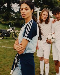 two men and a woman standing on a soccer field