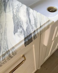 a white sink sitting under a faucet next to a marble covered counter top