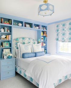 a blue and white bedroom with bookshelves on either side of the headboard