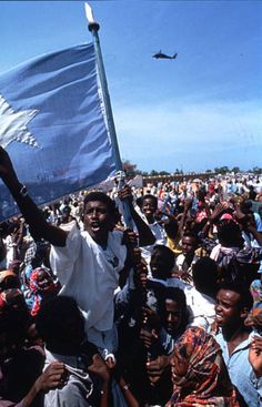 a large group of people standing next to each other in front of a blue and white flag