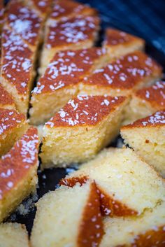 slices of cake sitting on top of a pan covered in powdered sugar and syrup