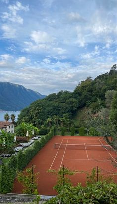 a tennis court surrounded by greenery and mountains