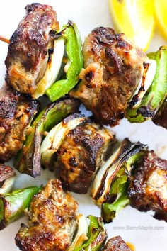 grilled meat and vegetables on skewers with lemon wedges in the background