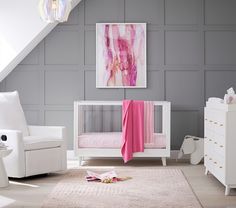 a baby's room with grey walls and white furniture