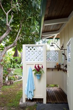 an outdoor shower is shown with flowers in the pot and towels hanging on the door