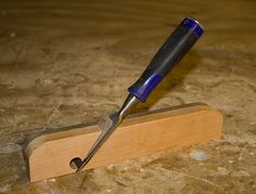 a knife that is sitting on top of a piece of wood with a blue handle