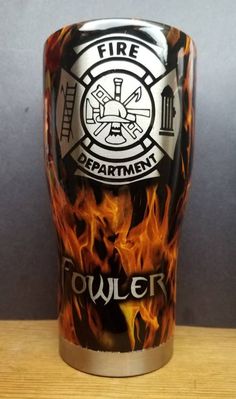 a fire department tumbler cup sitting on top of a wooden table next to a wall