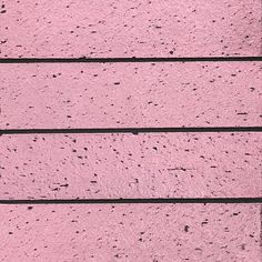 a black and white cat laying on top of a pink brick wall next to a window