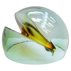 a glass sculpture with an orange and yellow bird on it's back end, sitting in front of a white background