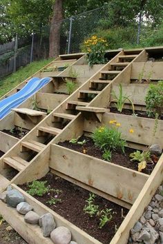 an outdoor garden with wooden steps leading up to the water slide and flowers growing in it