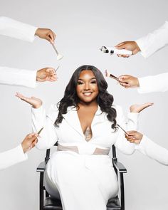 a woman sitting in a chair surrounded by hands