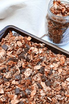 a pan filled with chocolate granola next to a jar of nuts