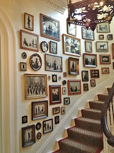 a staircase with many pictures on the wall and a chandelier hanging above it