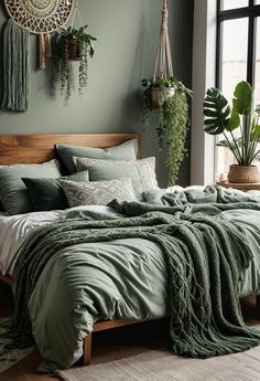 a bed with green sheets and pillows in a bedroom next to a large window filled with potted plants