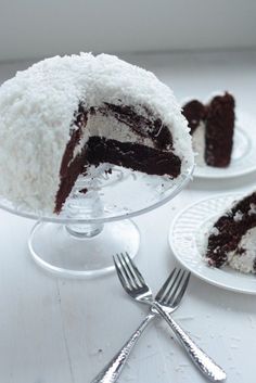 two pieces of chocolate cake on plates with forks