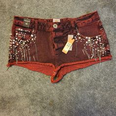 a pair of red shorts with beads and chains on the side, sitting on carpet