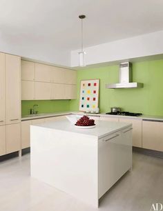 a large kitchen with green walls and white counter tops, along with an island in the middle