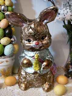 an easter bunny figurine next to some flowers and eggs