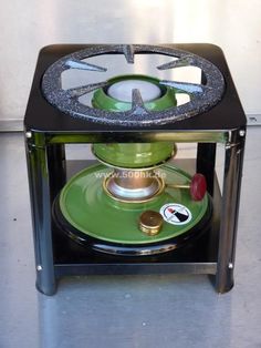 a green stove sitting on top of a metal stand