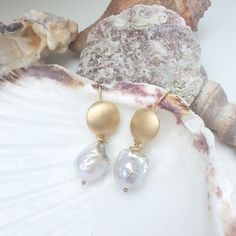 These earrings embody understated elegance and timeless beauty. A polished, gold-plated round disk forms the hook, its smooth surface gleaming with a warm, radiant glow. Suspended from this luminous disk is a single, exquisite baroque white pearl. The pearl’s organic shape, with its natural curves and unique irregularities, contrasts beautifully with the sleek simplicity of the gold. Together, the golden disk and the Keshi pearl create a harmonious blend of modern sophistication and nature’s raw White Gold Pearl Earrings, Forever Jewelry, Gold Pearl Earrings, Jewelry Ring Box, Keshi Pearls, Men's Jewelry Rings, Natural Curves, Understated Elegance, The Pearl